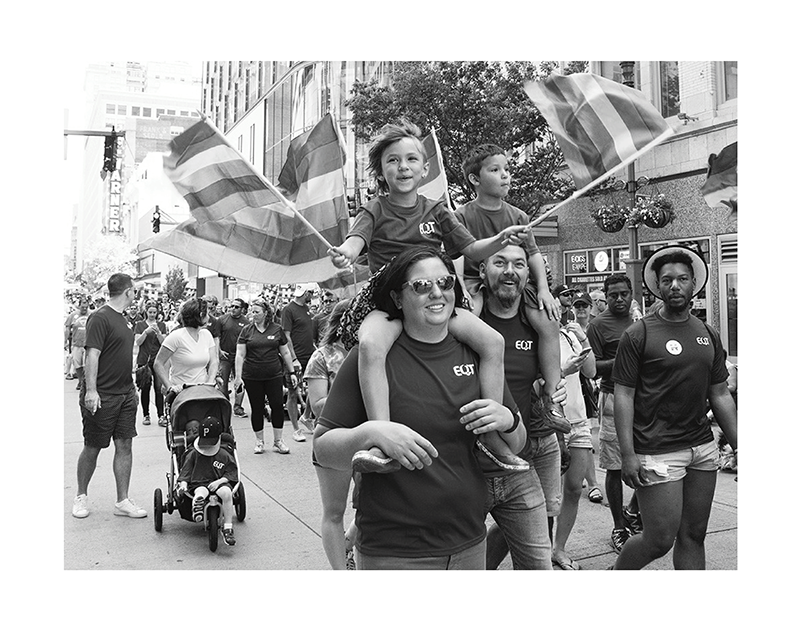 Mother and son wave pride flags at a pride parade.