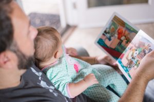 an image of a father reading a story to a baby.
