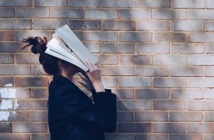 An image of a woman burying her head in a book.