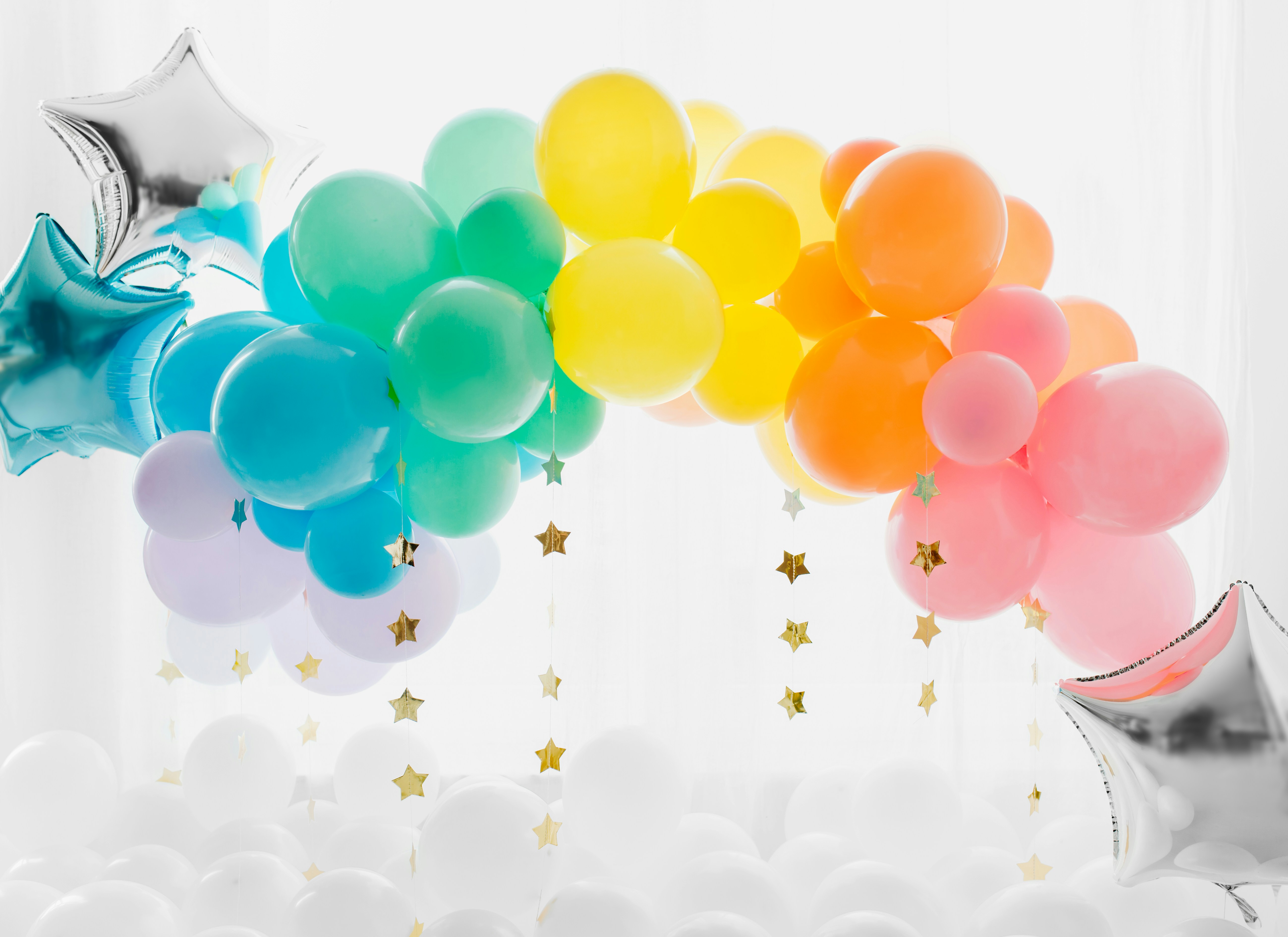 A colorful balloon arch with star-shaped decorations hanging down, set against a bright background.