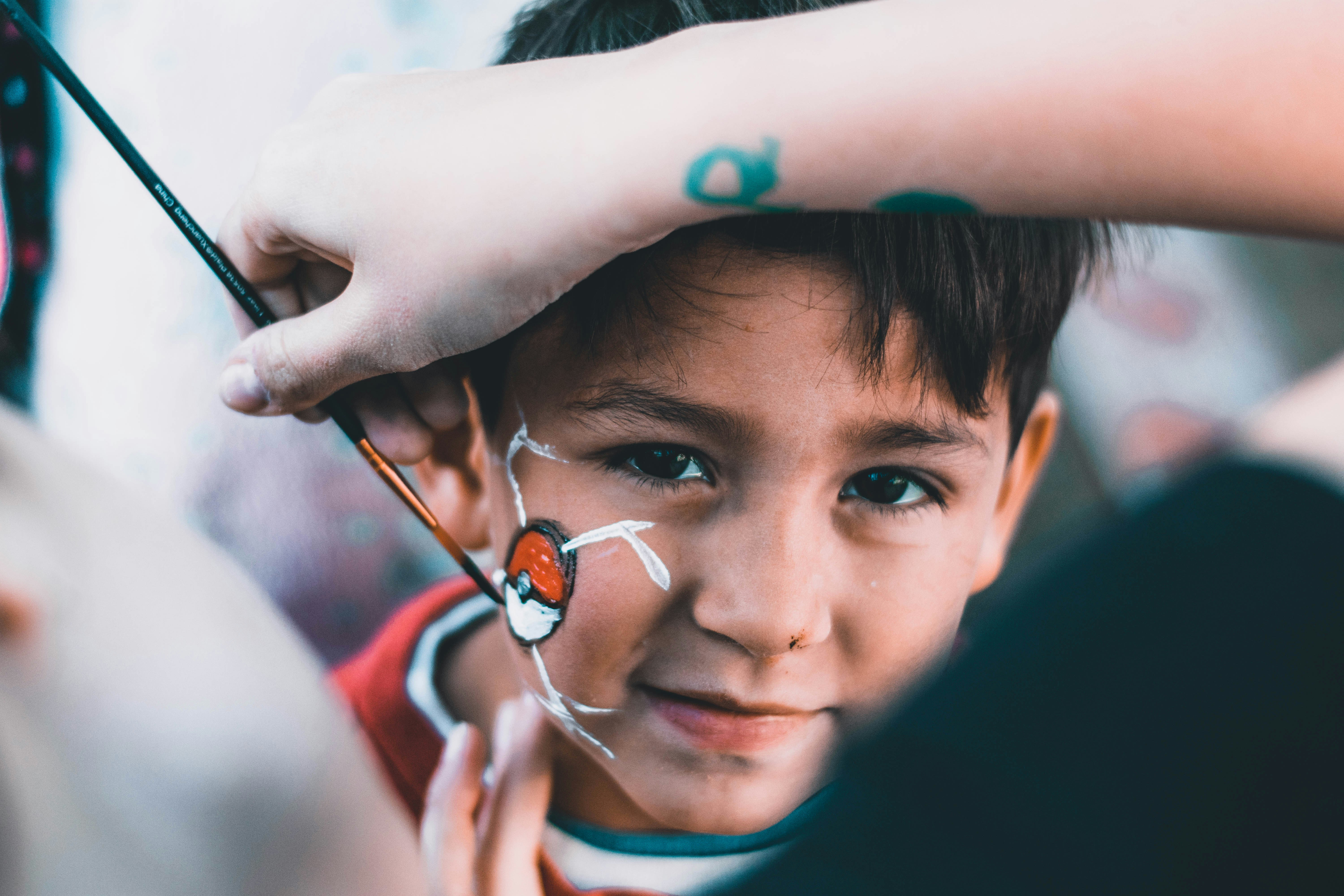 A boy having a pokemon ball painted on his face