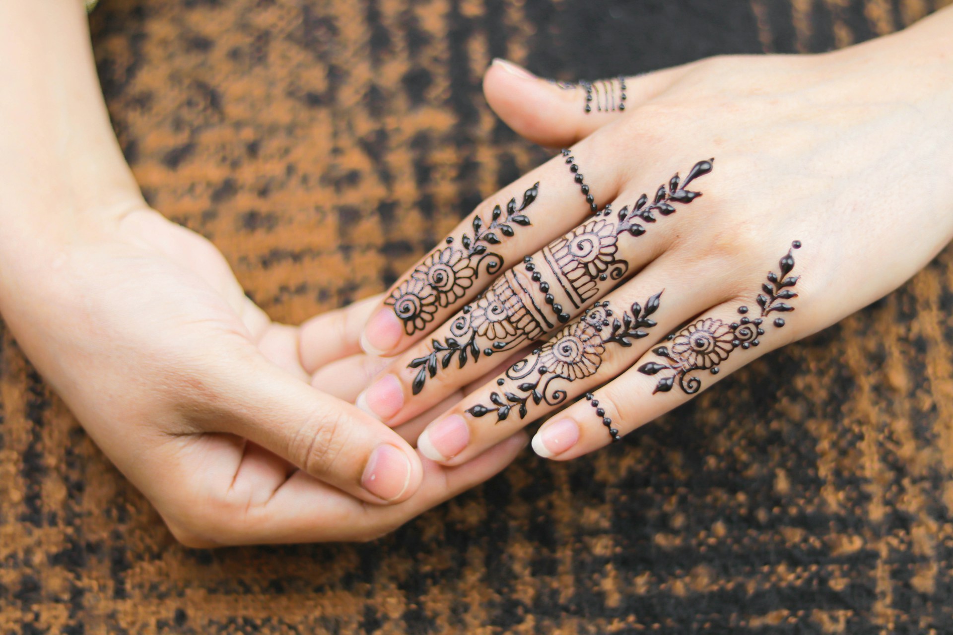 A close-up image of a person’s hands adorned with intricate henna designs