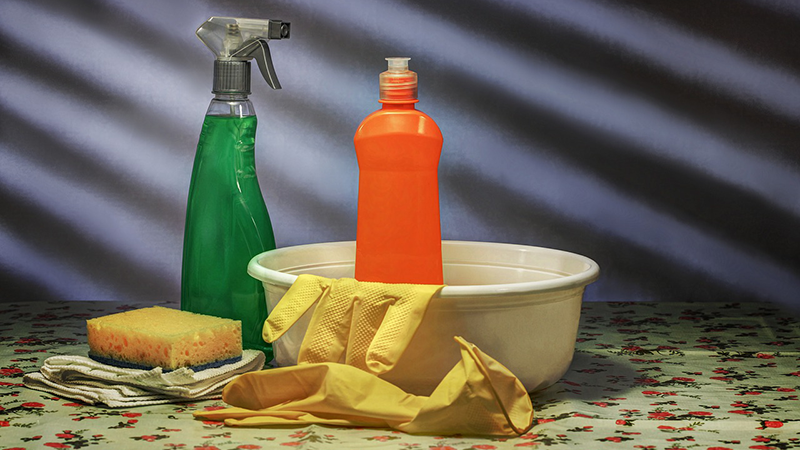 a soap bottle, a spray cleaner, a sponge, a cloth, a container, and a pair of gloves