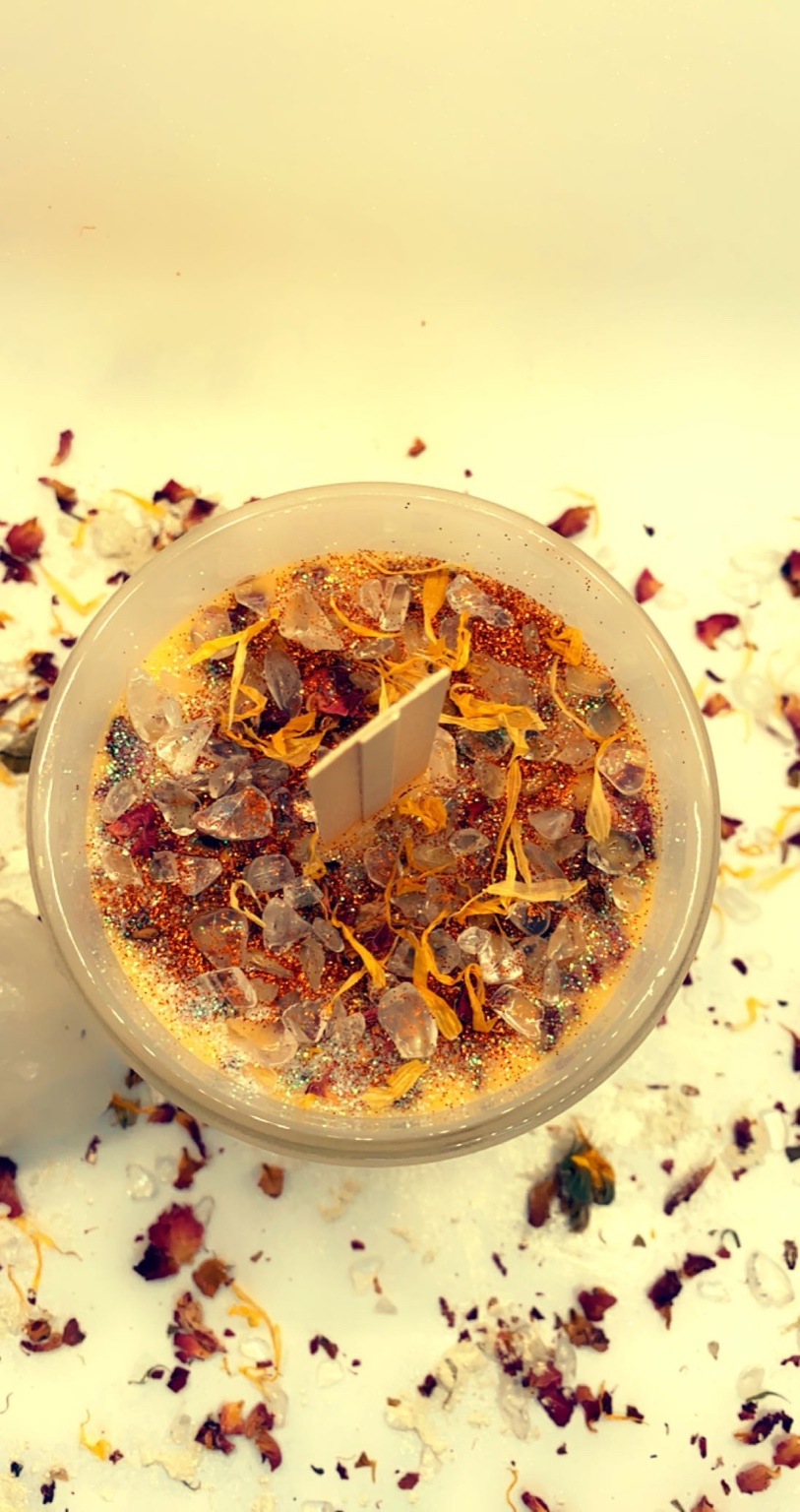 Golden-toned candle surrounded by botanicals and shimmering textures.