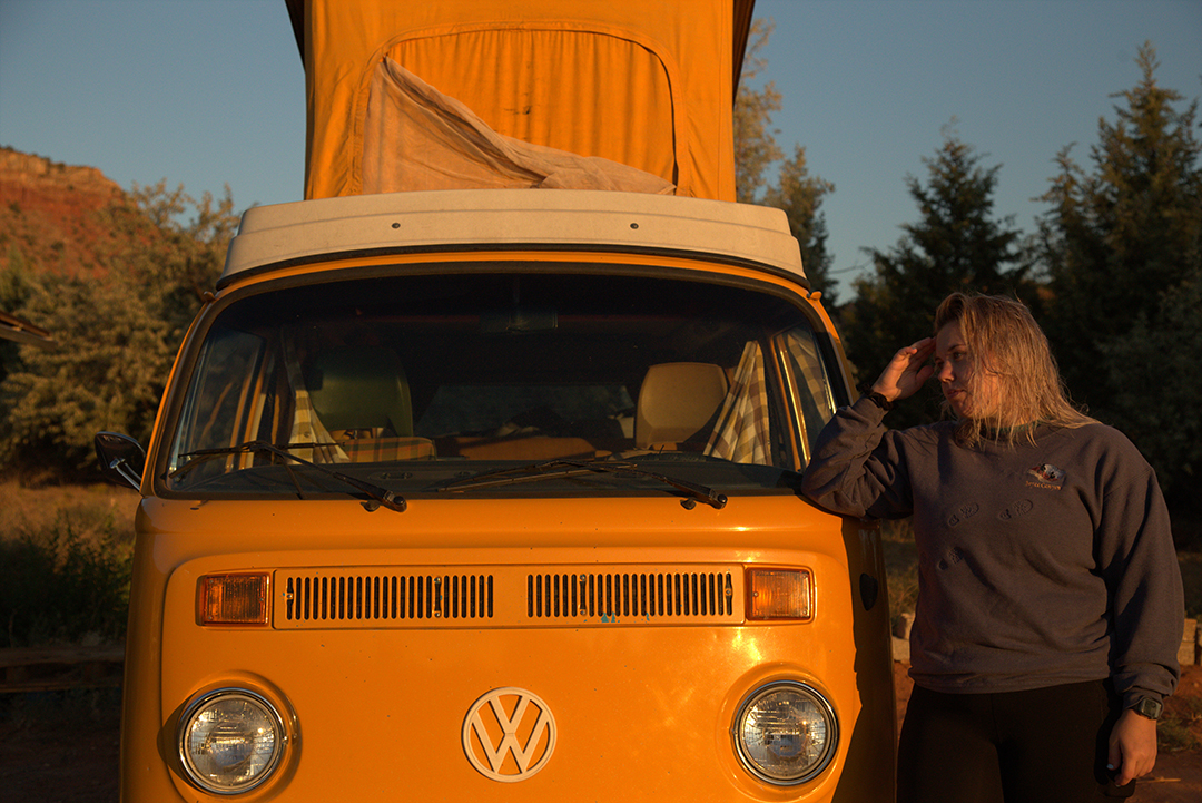 A girl leaning against a yellow van.