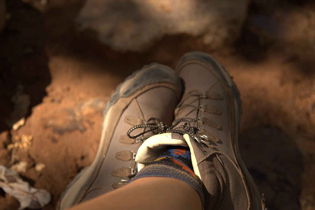 A pair of hiking boots being worn while resting.