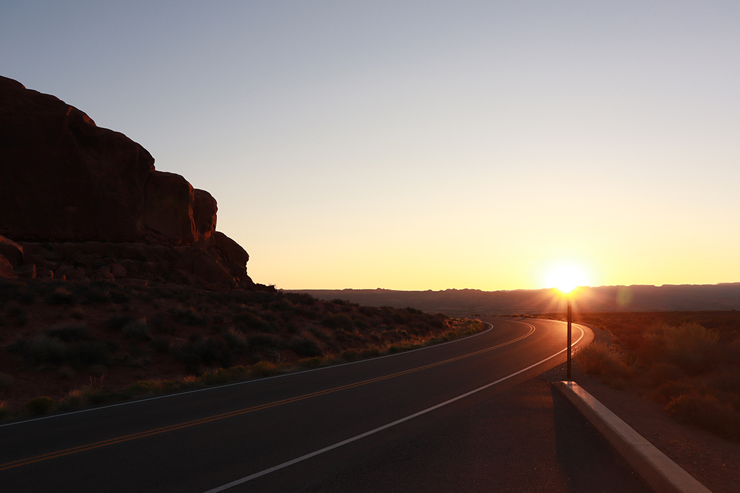 A landscape image of the sunrising over the mountains of Arches Naitonal Park.