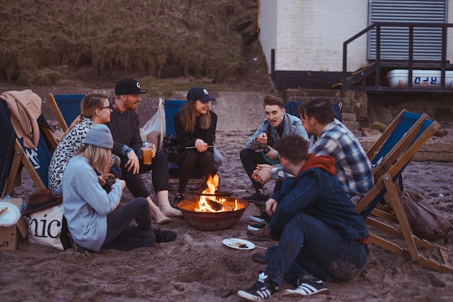 7 friends sitting around a campfire talking and laughing.