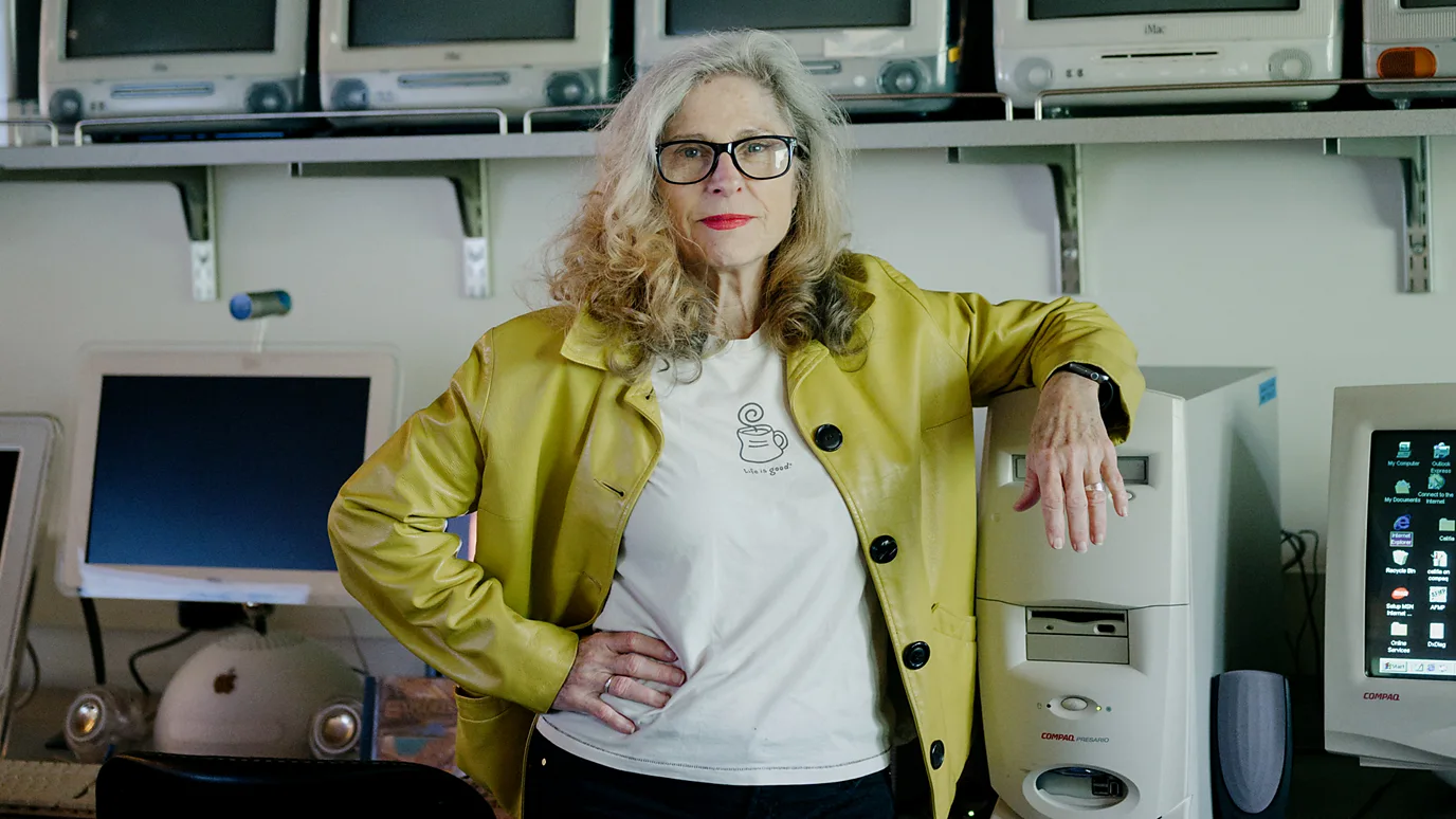 Dene Grigar smiles in front of vintage Windows computer