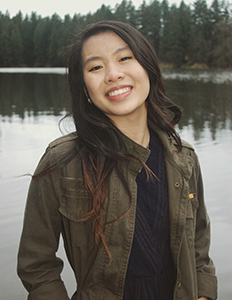 Grace Rouleau standing on a dock wearing a green jacket and a blue dress.