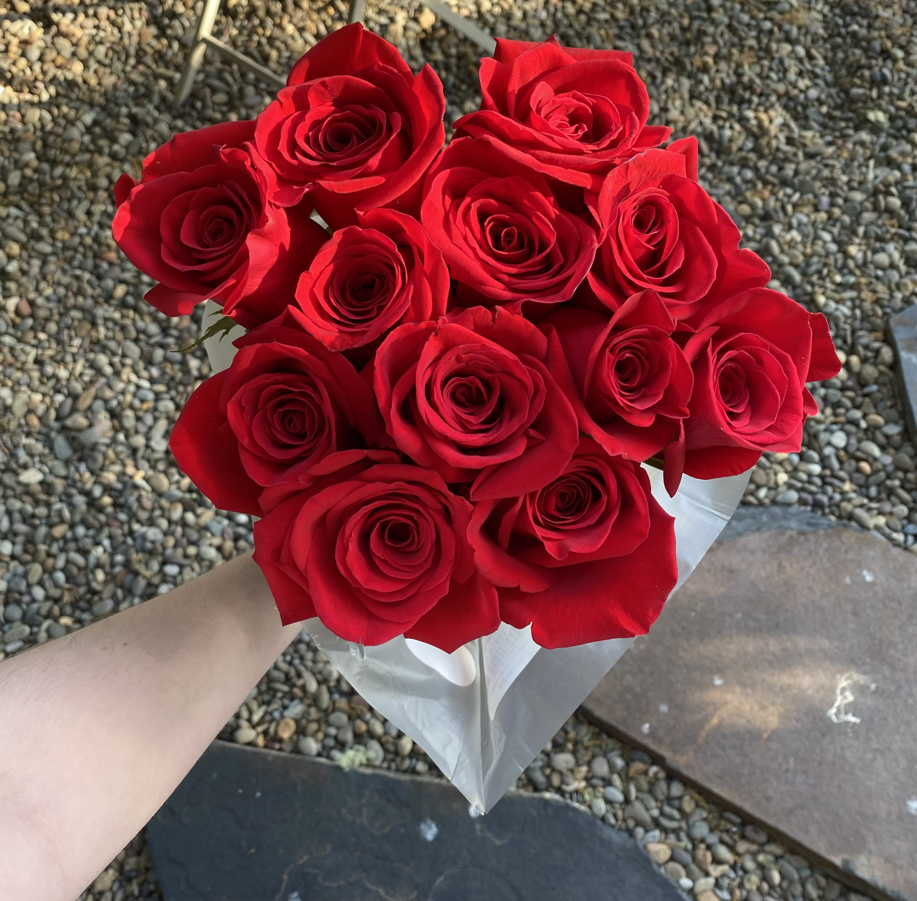 a bundle of red roses with a gravel background