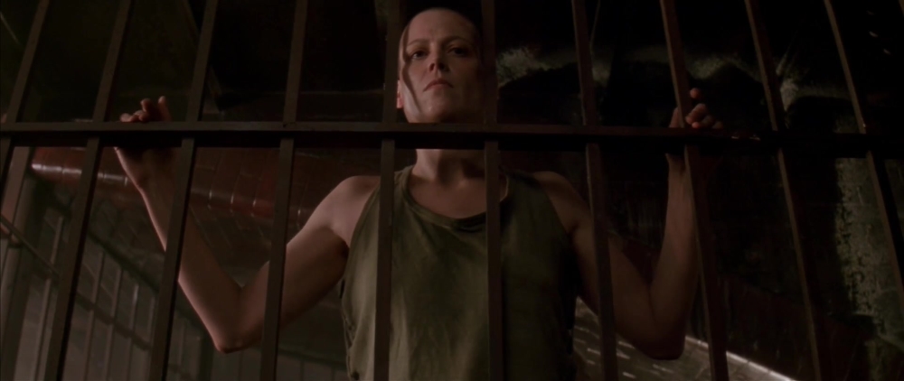 Ellen Ripley standing behind bars
