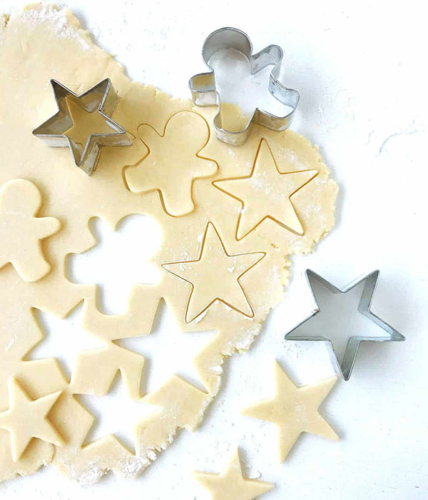 Cookie dough cut into star and gingerbread shapes.