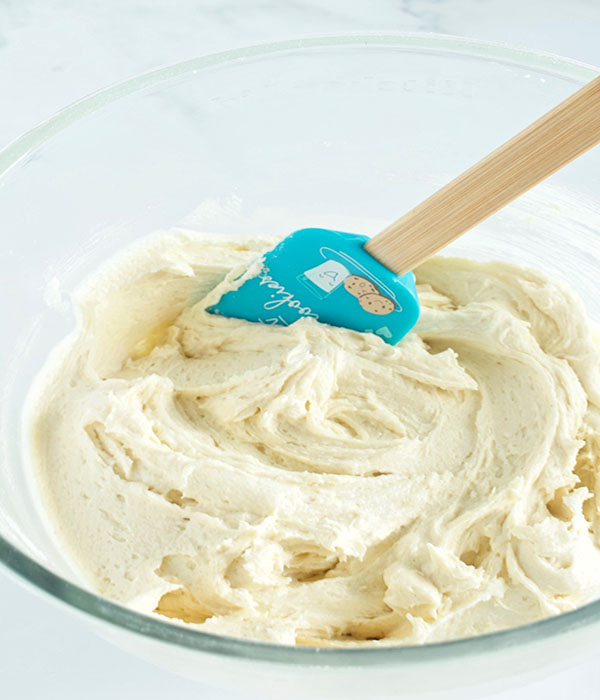 Creamy cookie dough in a mixing bowl with a spatula.