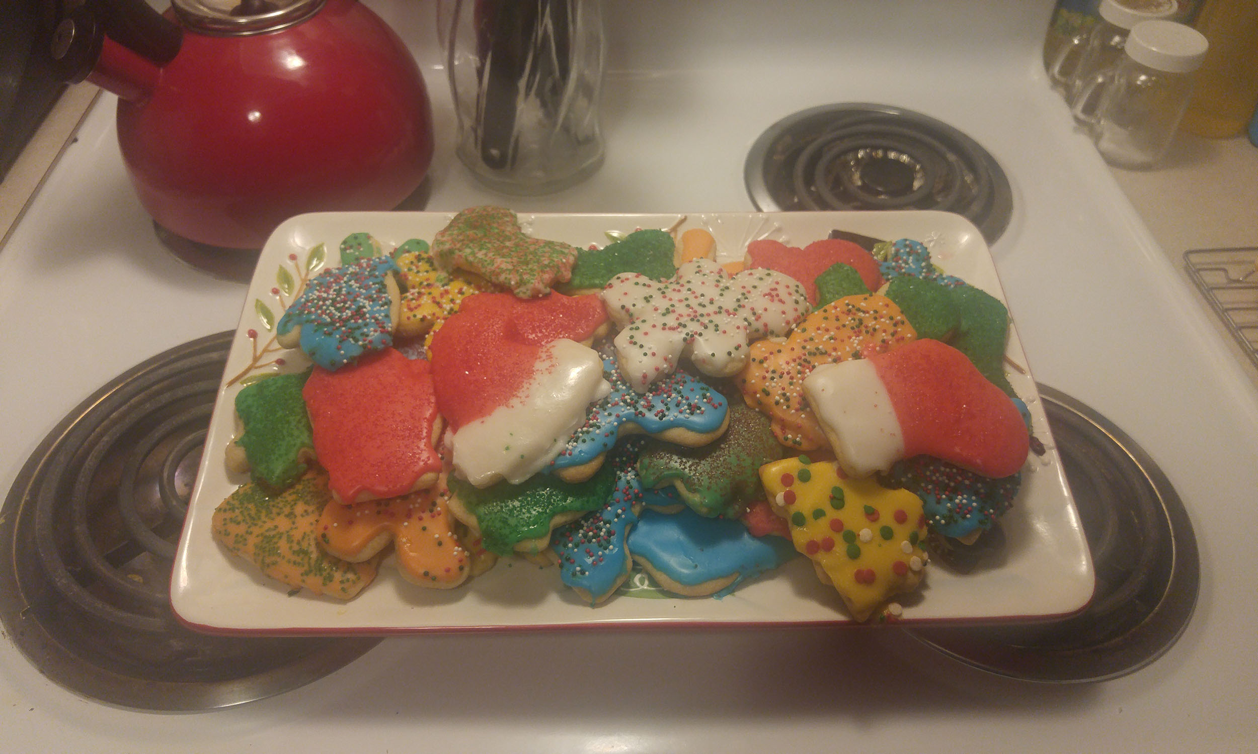 Festive Christmas cookies with icing and sprinkles on a plate.