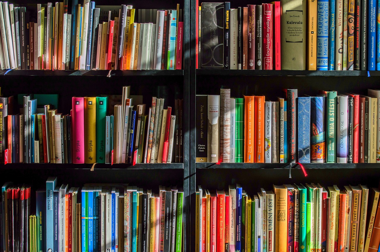 two black bookshelves with three shelves each, filled with many colorful books.