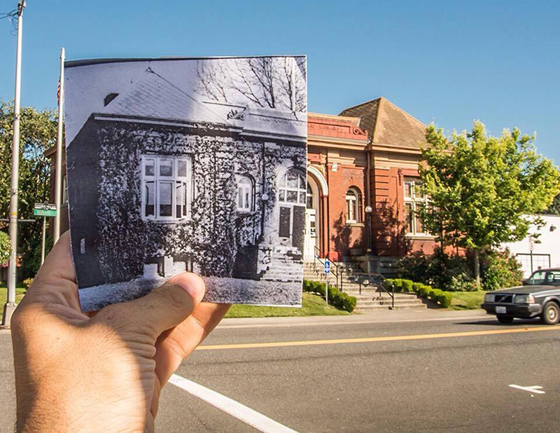 Hand outside holding grayscale image of brick building over street view of building, Clark County Historical Museum