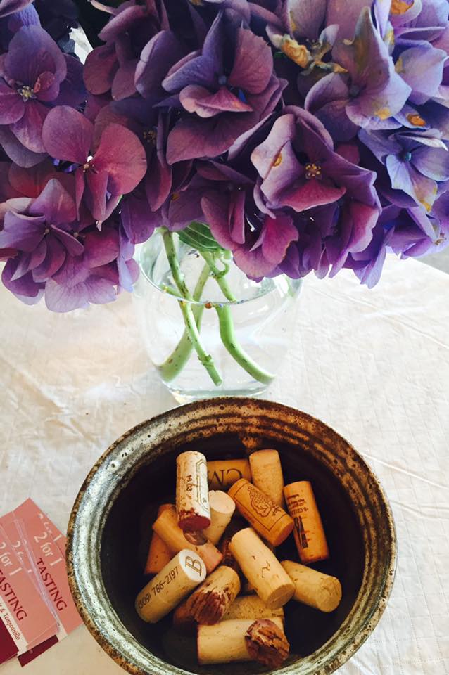 A bouquet of flowers pictured above a bowl of wine corks.
