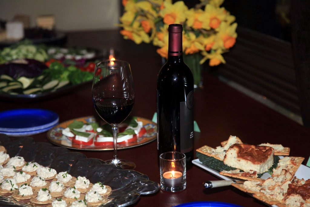 A glass of wine and surrounding appetizers.