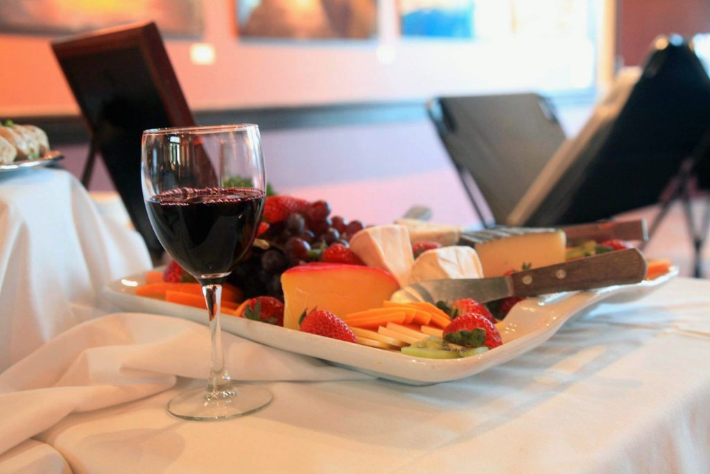Wine and a cheese and fruit platter pictured together on a table.
