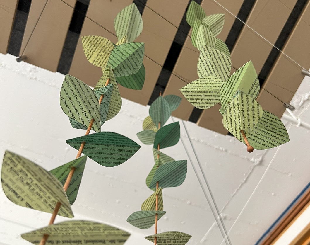 Stems of reed made with book pages covered in Dura-Lar hanging from the ceiling