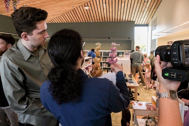 Two people assessing stems of flowers made from book pages