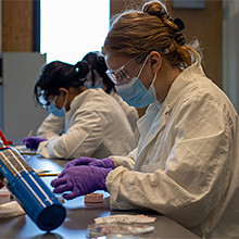 WSU Vancouver Scientist using a lab microscope.