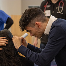 A WSU Vancouver Scientist inspecting another student with a neurology tool.
