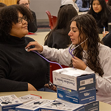 Scientist practicing using stethoscope on another scientists chest