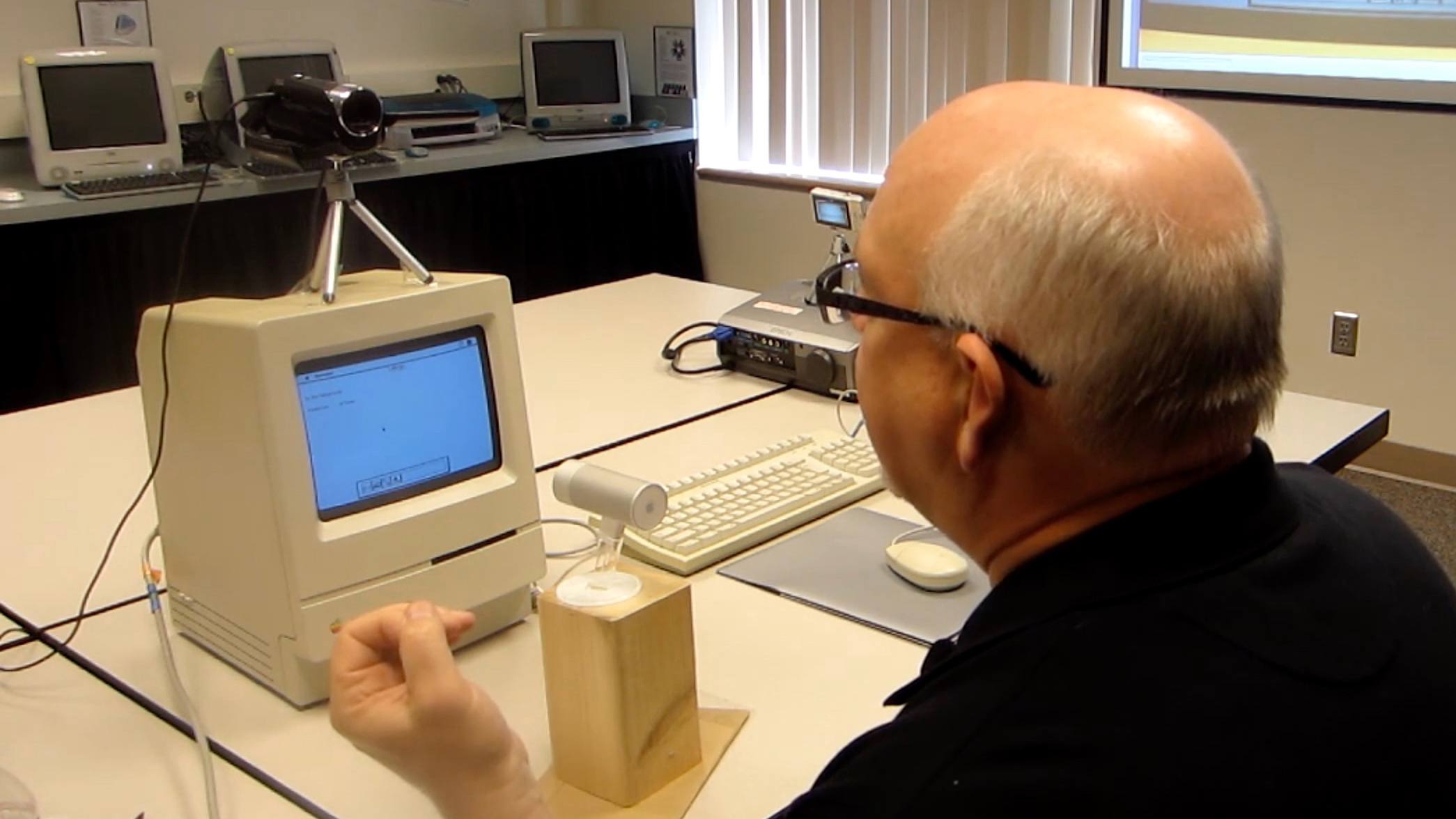 Stuart Moulthrop sitting infront of a camera, microphone, and classic Macintosh computer