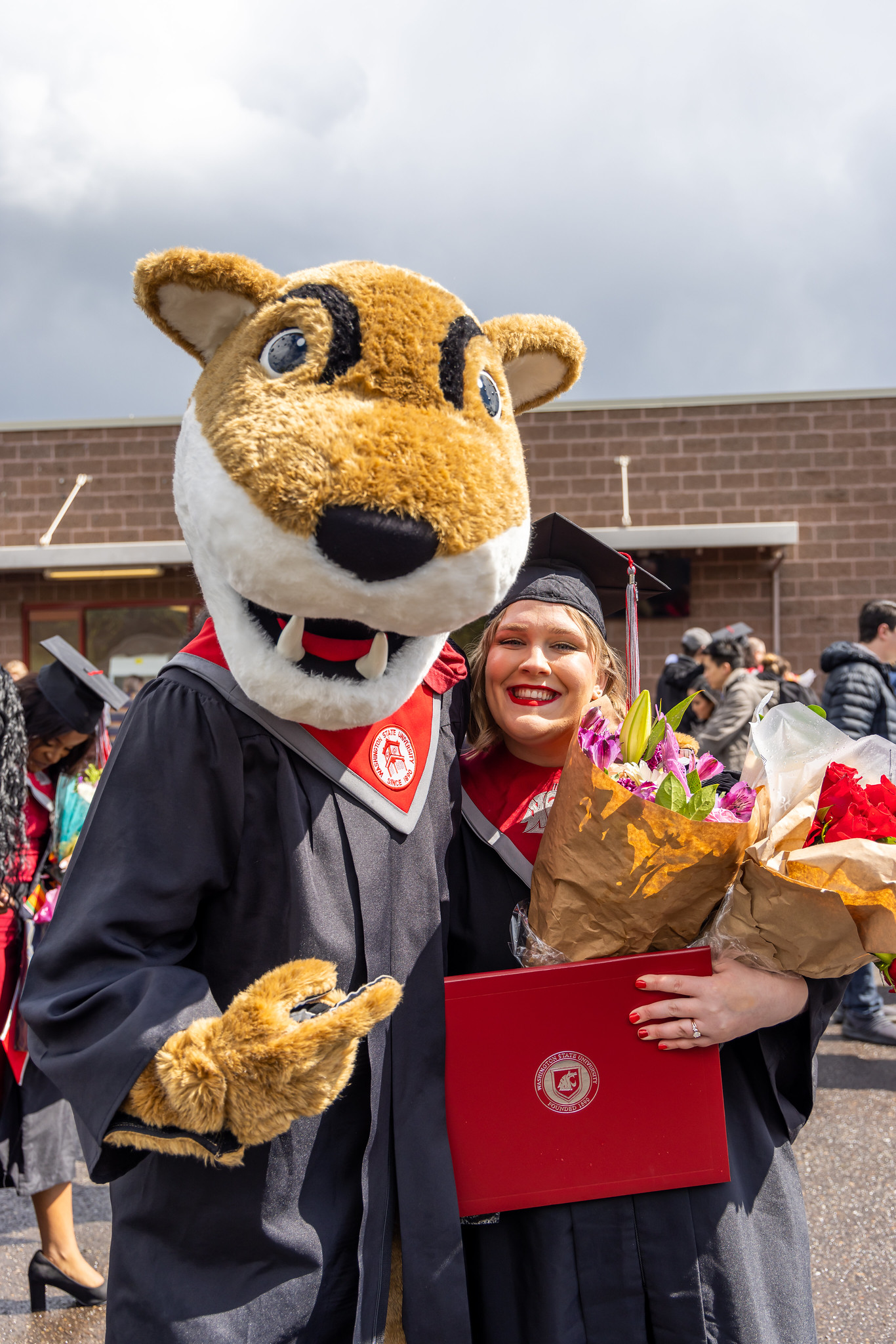 WSU mascot with a student at graduation ceremony