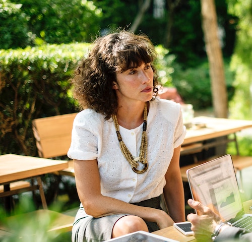 woman in professional attire in a meeting outside on a bench 